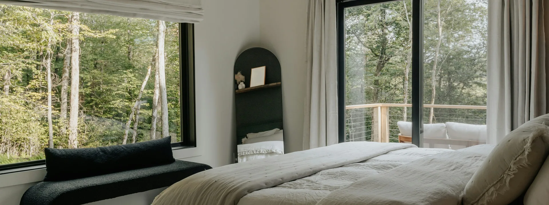 Bedroom with a large window looking out on the forest