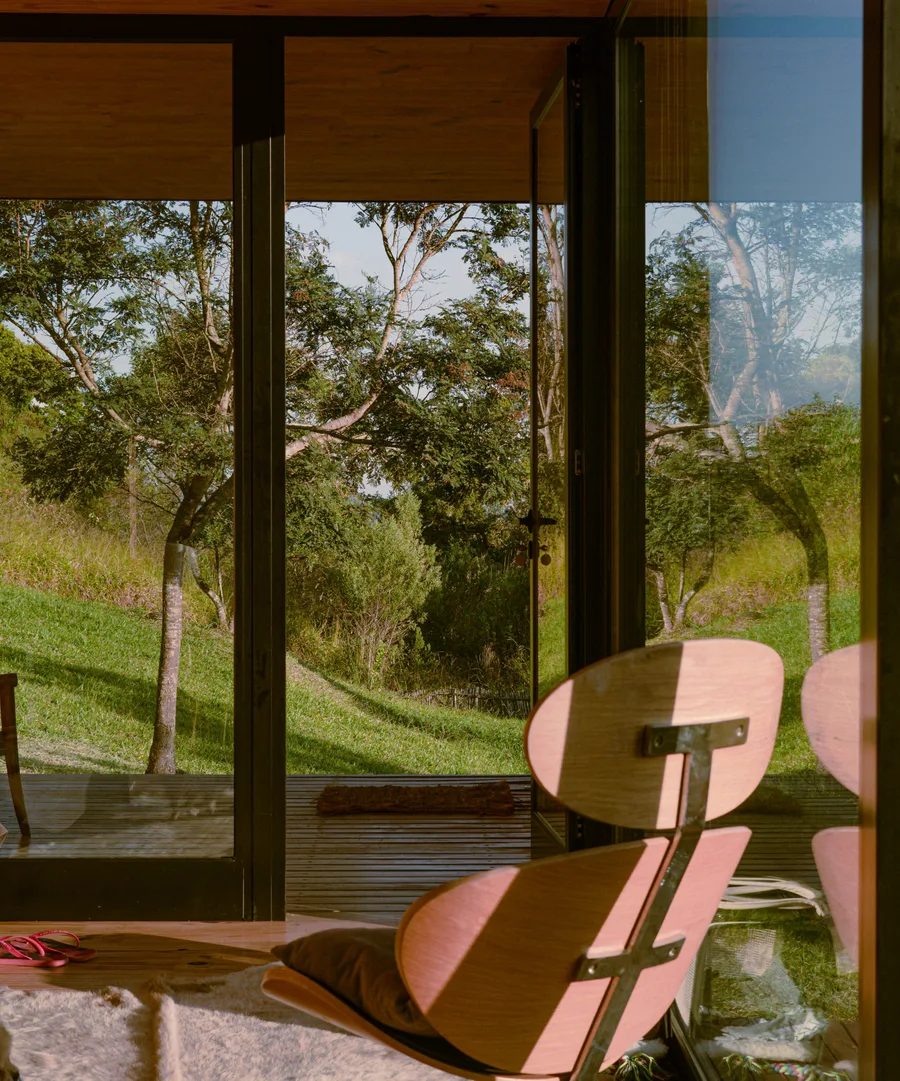 Interior of a glass cabin looking out over a meadow