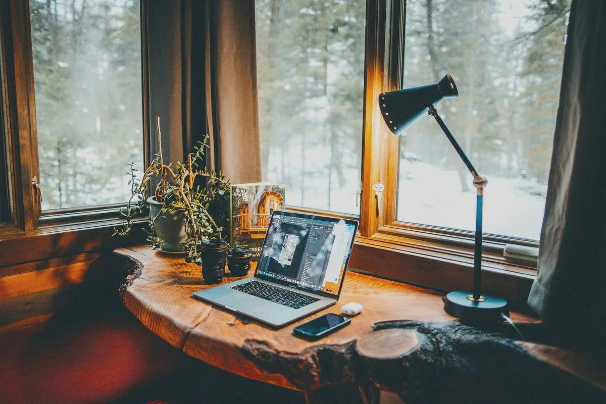 Laptop auf einer Holzarbeitsplatte am Fenster mit Blick auf verschneiten Wald